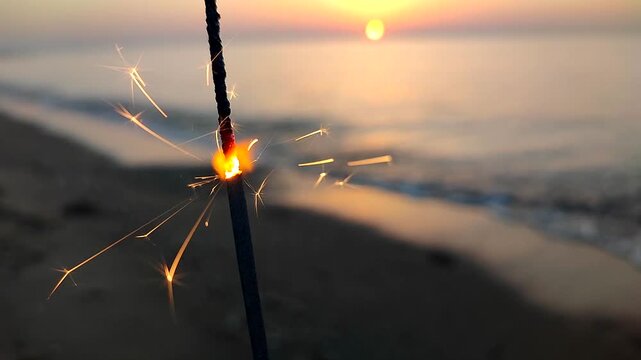 Bengal fire sparkler and man running past on sandy beach by sea. Bengal fire sparkler burning and sparkling on the sand on the beach of the sea coast during the dawn of sunset. Bengal light at sea.