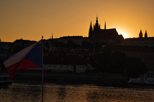 Czech flag waving with Prague Castle skyline at sunset