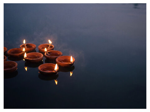 Clay oil lamps floating on dark water at night