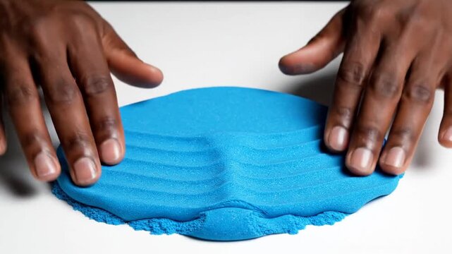 A person molding blue kinetic sand