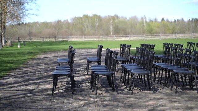 Black chairs stand in rows outside. Preparations for a wedding ceremony.