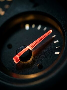 Glowing red needle on car dashboard gauge, illuminated automotive speedometer dial, close up of vehicle instrument panel at night