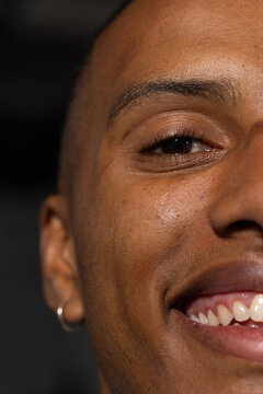 Adult African American man smiling, squinting and showing teeth in studio with silver hoop earring