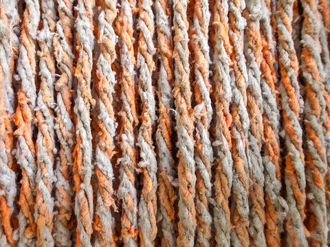 Close up of twisted orange and grey cotton mop strands for cleaning and industrial texture.