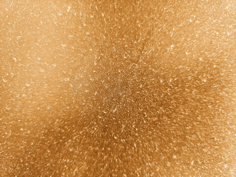 Abstract golden glitter background with sparkling light particles and warm bronze texture.
