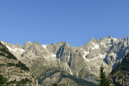 Scenic landscape of the rugged rocky peaks of the Mont Blanc massif under a clear blue sky during summer, Courmayeur, Aosta Valley, Italy