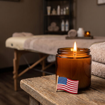 Scented candle with american flag on wooden table inside wellness spa.