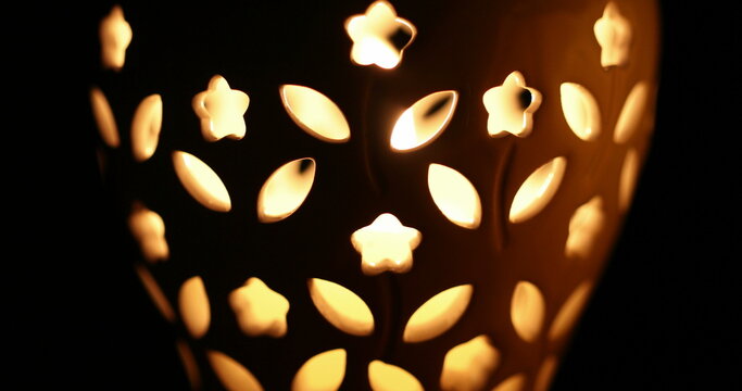 Closeup candle burning inside vase with holes