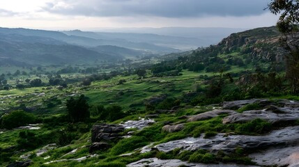 Fototapeta premium A lush green valley with rocky terrain and rolling hills under a cloudy sky offering a serene natural landscape
