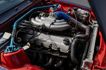 Fototapeta premium Detailed close-up shot of a modified vintage car engine bay featuring an aftermarket aluminum intake manifold custom cylinder head and performance strut brace
