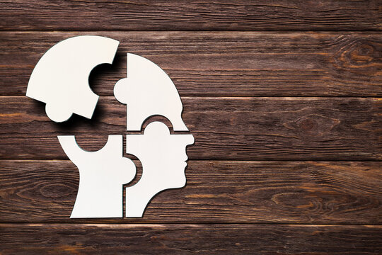 Mental health concept. Human head puzzle pieces on wooden background.