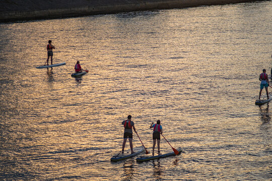 people paddleboarding on a river at sunset
