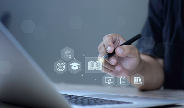 Online course training, digital knowledge database, and skill development concept with hand using stylus pen pointing at glowing book and e-learning HUD icons on laptop screen.