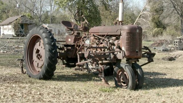 An old rusty tractor sits idle as it rust in the sun.