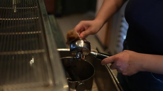Close up of barista cleaning espresso portafilter with brush