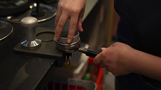 Close-up of barista hands leveling ground coffee in a portafilter