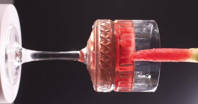 a glass of red watermelon cocktail and a slice of watermelon
