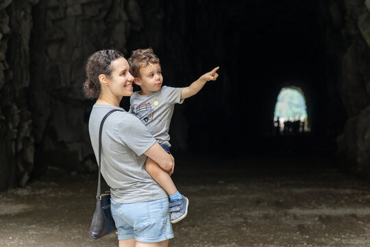 Mother Carrying Son Pointing Toward Light Inside Tunnel At Othello Tunnels Hope BC Canada