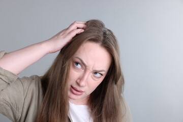 Fototapeta premium Dandruff problem. Woman examining her head on grey background, space for text
