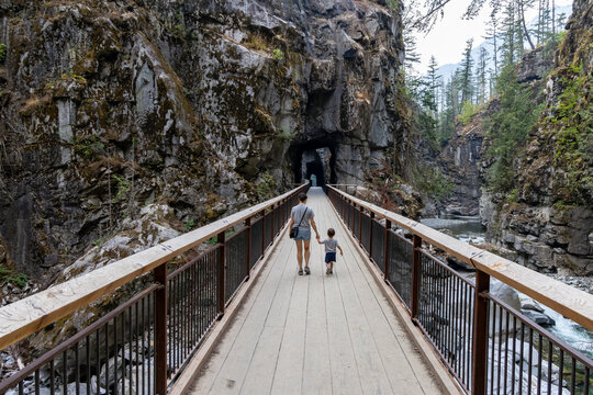Family Walking Hand in Hand on Wooden Bridge Toward Tunnel at Othello Tunnels Hope BC Canada