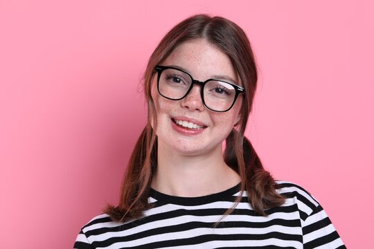 Beautiful teenage girl with freckles on pink background
