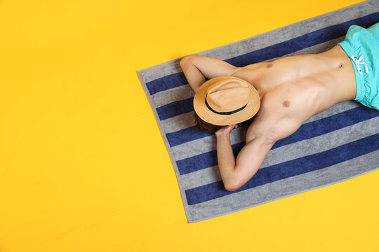 Man sunbathing on yellow background, top view. Space for text