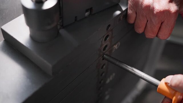 Close up of an old man's hand adding extra weight plates to a strength training machine during a workout in a gym. Concept of equipment, adjustment process, progressive overload, health, and fitness