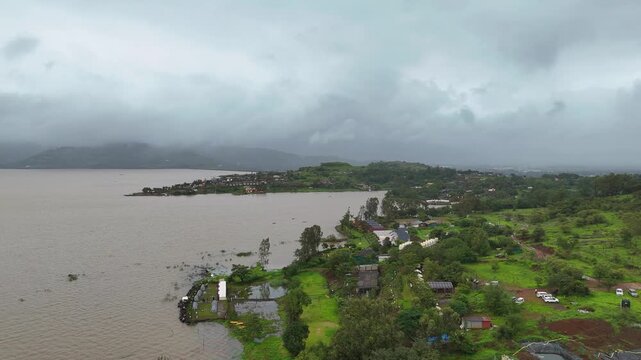Expansive aerial drone view of scenic Pawna Lake reservoir surrounded by lush green hills under overcast monsoon sky⁠