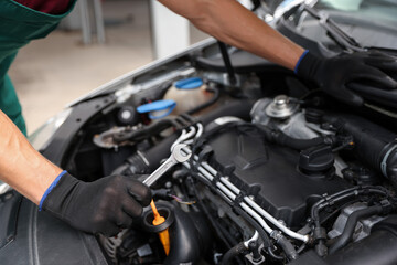 Fototapeta premium Professional mechanic with wrench fixing car indoors, closeup