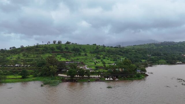 Expansive aerial drone view of scenic Pawna Lake reservoir surrounded by lush green hills under overcast monsoon sky⁠