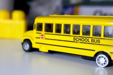 Side view of yellow toy school bus model on white table back to school concept © Yousra Saleh 