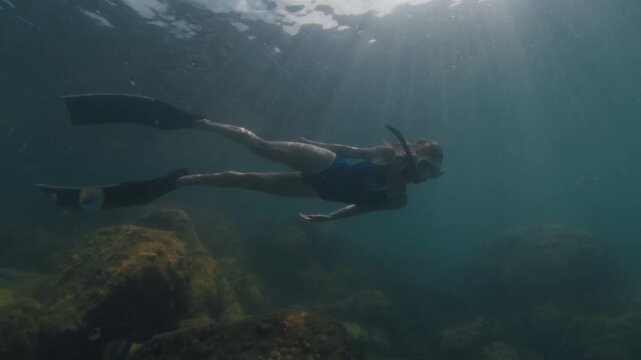 Young slim woman swims underwater, freediving and snorkeling in the sea near the coral reef near the island of Ilha Grande in Brazil