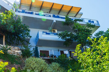 Beautiful view of modern hillside apartment building with balconies surrounded by Mediterranean...
