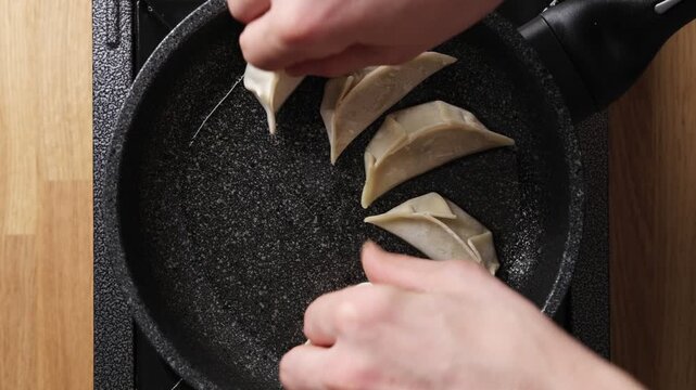 Timelapse shows gyoza arranged evenly in frying pan. Even gyoza spacing helps hot oil and steam cook every dumpling evenly. Single layer keeps gyoza separate for frying, steaming and easy serving.
