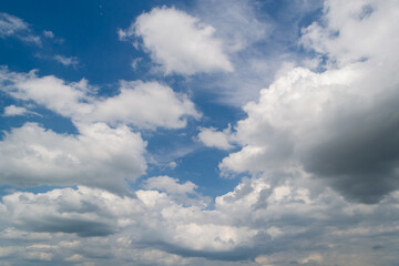 Obraz premium Scenic view of soft white cumulus clouds spreading across a vibrant blue sky during a clear daylight afternoon, ideal for nature background.