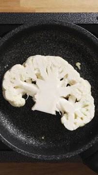 Culinary student places cauliflower in hot frying pan. Cauliflower needs hot pan, oil and no movement for golden sear. Cauliflower lesson teaches searing technique, heat control and safe pan handling.