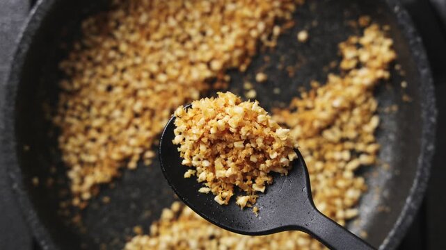 Cooking teacher shows toasted almond panko mix on spoon. Almond panko mix needs gentle heat and stirring for golden colour. Students use almond panko mix for cauliflower, fish, chicken or casseroles.