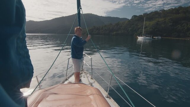 Young man enjoys the morning time on the sailing boat anchored in the calm bay