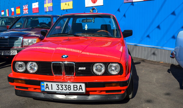 Vibrant red BMW E30, defining icon of 1980s German automotive culture, showcasing its legendary front fascia, quad round headlights, and signature split kidney grille