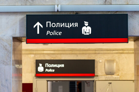 Directional sign for police station with text in Russian and English, featuring a police officer icon, located in a public building interior