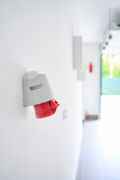 Red industrial electrical socket is mounted on wall inside garage