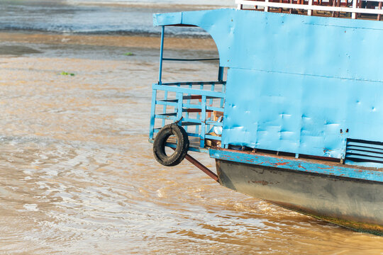 Blue boat moored along a muddy riverside