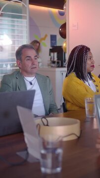 A woman leading a meeting, Diverse team of professionals engages in a productive meeting, utilizing laptops for data analysis and collaborative discussion in a vibrant, modern office environment