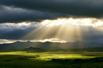 Naklejka premium Sunlight penetrates through gray clouds above green Icelandic pastures, mountains. Golden rays illuminate grassy fields beneath a cloudy sky at sunrise. A picturesque rural scene displays striking wea