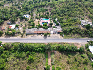 Fototapeta premium Aerial drone view shows vibrant ranch with blue pool and buildings, highway, lush tropical nature in Guerrero, Mexico, sunny day