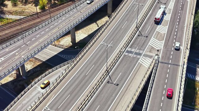 Several vehicles travel on a multi-level highway. A bus moves along one lane while other cars occupy separate paths on a sunny day. The scene shows urban infrastructure.
