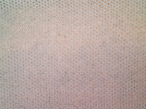 Close-up texture of light beige perforated fabric on car pickup roof lining, breathable mesh material, uniform small holes pattern, automotive interior surface.