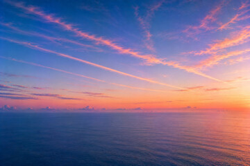 Fototapeta premium Pink sunset clouds over calm blue ocean and distant horizon