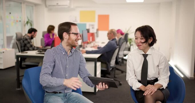 People working together in an office space discussing ideas and sharing a device at a business meeting