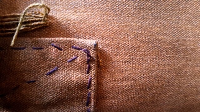 Brown fabric pocket featuring rustic purple hand stitched decorative seam details